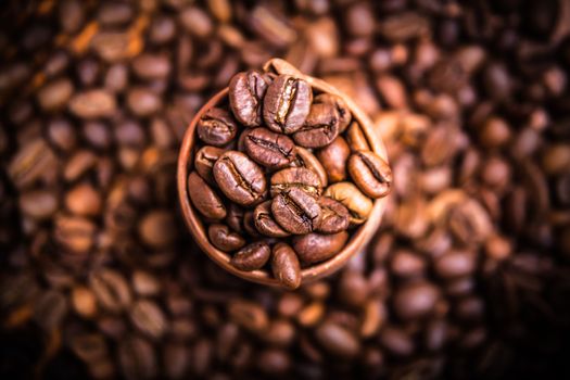 black coffee beans in a wooden cup, close-up