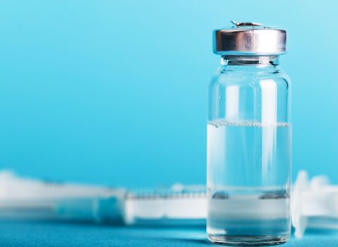 bottle of medicine and syringe close-up on a blue background