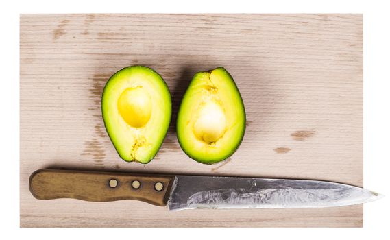two pieces of fresh avocado and knife on a wooden board