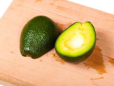 two pieces of fresh avocado close-up on a wooden board