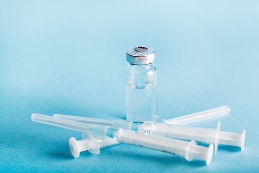 bottle of medicines and syringe on a blue background