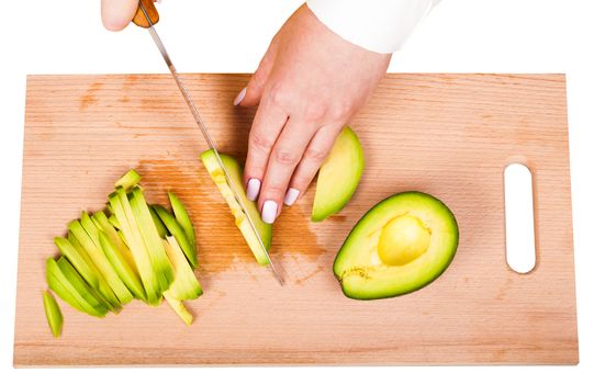 chef slicing the avocado on a wooden board