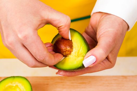 chef removes bone from fresh avocado closeup