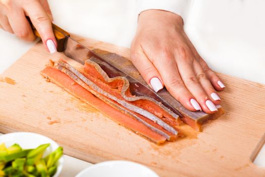 chef cuts the fillet of red fish closeup on a wooden board