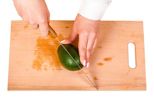 chef cuts the avocado on a wooden board