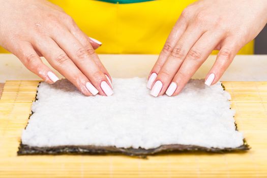 cook places the rice on the nori sheet closeup