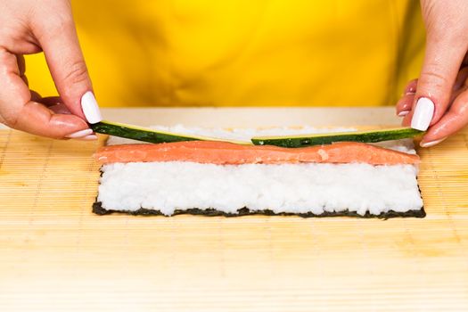 cook places the a stuffing on the nori sheet with rice