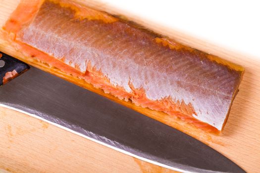red fish fillet and knife close-up on a wooden board