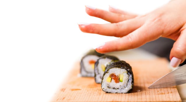 cook hand cuts the roll closeup on a wooden board