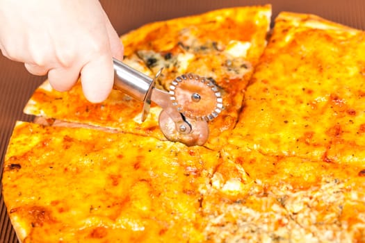 hand with a knife cuts the pizza closeup