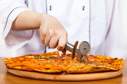 chef with knife cuts the pizza closeup