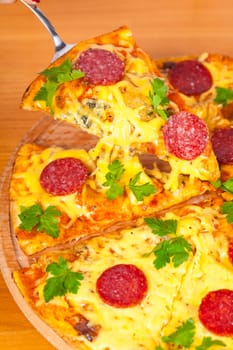 hot slice pizza with salami on wooden background