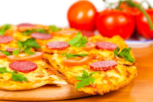 hot pizza with salami on background ripe tomato