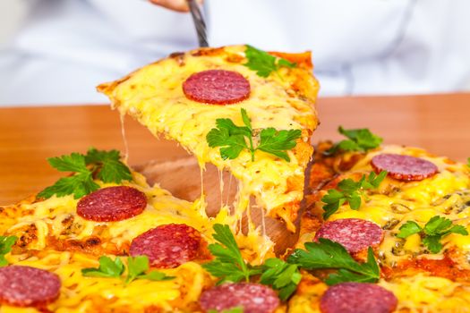 slice pizza with salami on wooden background