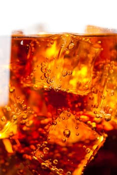 Cola with ice cubes and bubbles closeup