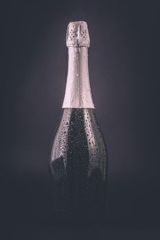 bottle of champagne in the drops of water on a dark background