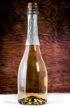 Closed bottle of sparkling wine on a wooden background