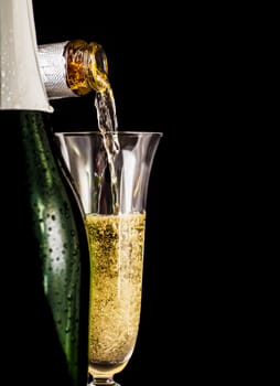 Champagne is poured into glass on a dark background