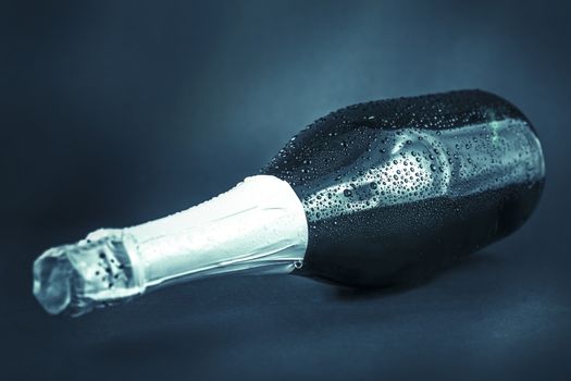 bottle of champagne in the drops of water on a dark background