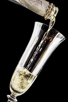 Champagne is poured into wine glass on a dark background