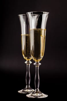two glasses filled with champagne on a dark background