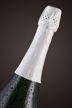 bottle of champagne in the drops on a dark background