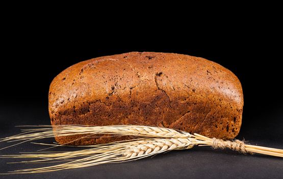 brown bread with ears of wheat on a dark background