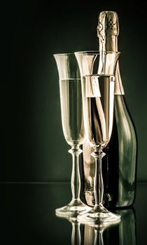 bottle of champagne with two full glasses on a dark background