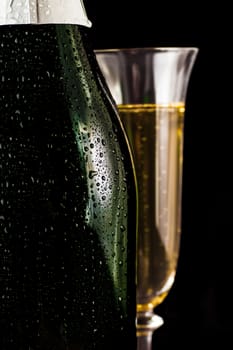 bottle of champagne with a glass closeup on a dark background