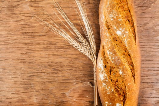 bread with ears of wheat on the wooden background