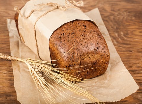 bread in a paper packing with ears of wheat on the wooden background