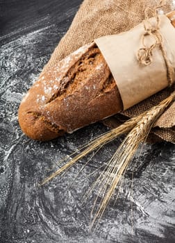 long loaf with ears of wheat on a dark background