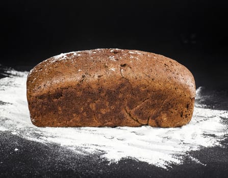 brown bread on a dark background with flour