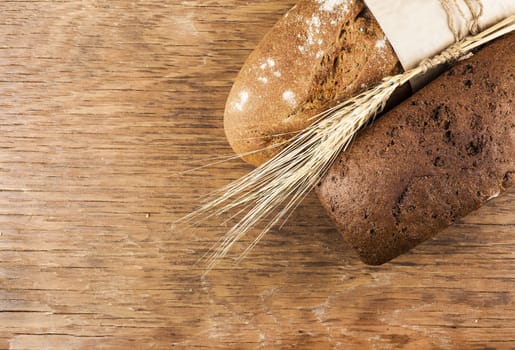 two rye bread with ears of wheat on the wooden background