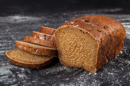 Black sliced bread on a dark background with flour