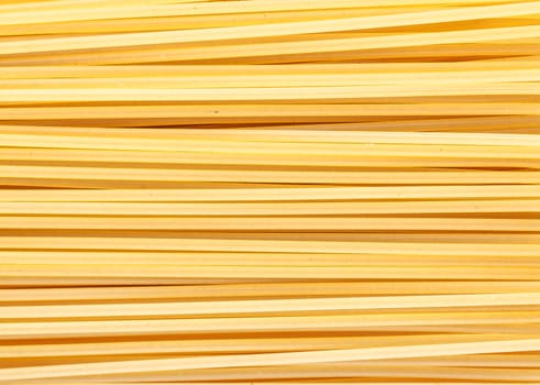 yellow background the raw pasta lying horizontally