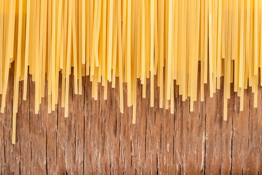 uncooked spaghetti posted on the a row on a wooden background