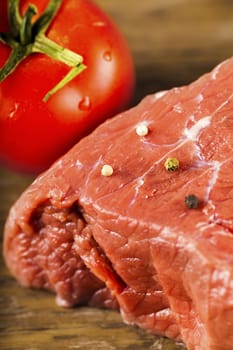 beef filet with herbs and tomato on a wooden background