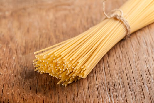 raw pasta tied with a rope on a wooden background