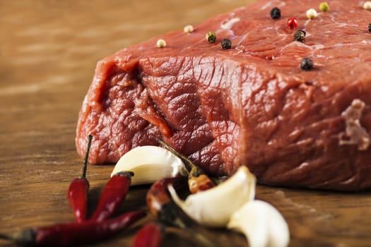 raw fillet of beef with spices on a wooden background