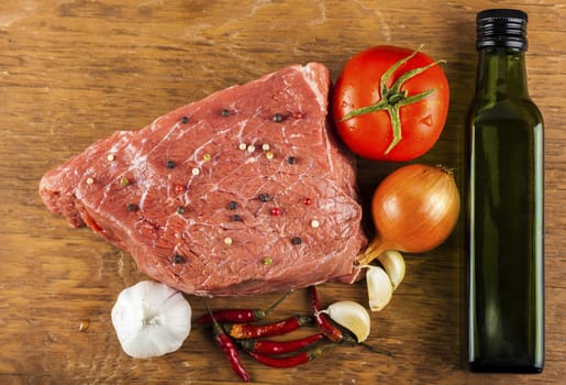 raw beef fillet with spices and vegetables on wooden background