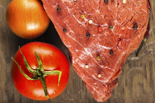 fillet of beef with spices and vegetables on wooden background