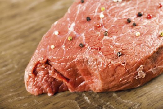 raw beef filet with spices on a wooden background