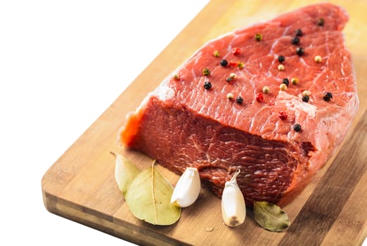 raw beef filet with spices on a wooden board, white background