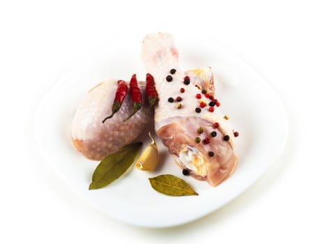 raw chicken feet on the plate with spices, white background