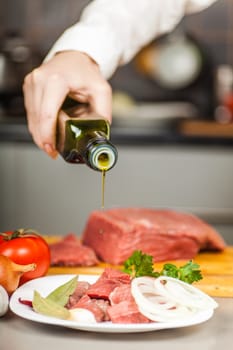 Chef pours olive oil on beef fillet