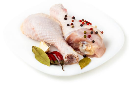 raw chicken feet on the plate with spices, white background