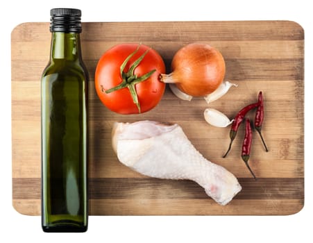 raw chicken leg on a wooden board and vegetables, white background