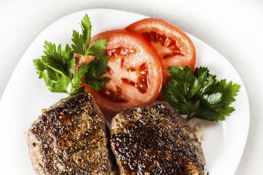 freshly made medallion on a plate with slices of tomato