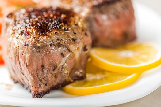 freshly made medallion on a plate with lemon wedges